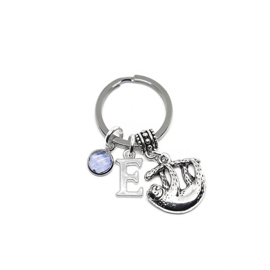 A silver keyring with a personalised charm featuring a birthstone and a letter, attached to a larger charm in the shape of a sloth.