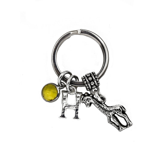 A silver keyring with a charm of a giraffe and a birthstone charm, along with a letter charm, attached to a split ring.